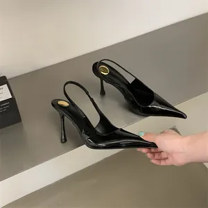 Detail view of black patent leather slingback heels with pointed toe and stiletto heel