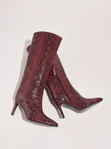 Detailed view of red snakeskin patterned high-heeled boots with pointed toe and side zipper