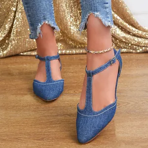 Close-up of blue denim T-strap flats for women with white stitching and adjustable buckle.