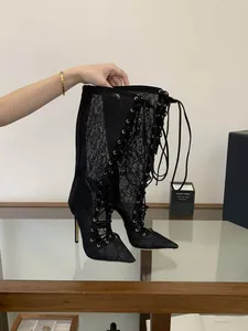 Close-up detail of black lace mesh stiletto boots featuring a front lace-up design