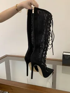 Detailed view of black lace mesh high heel boots with stiletto heel and lace-up front