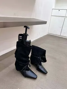 Gros plan de bottes plissées noires à bout pointu avec détail de lien sur la tige