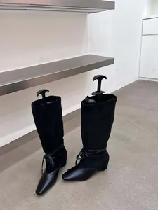 Vue détaillée de bottes plissées noires rétro à bout pointu avec détail de nœud à la cheville