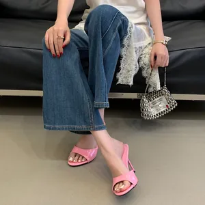 Close-up of pink glossy high-heel mules with stiletto heels and open-toe design.