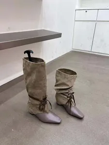 Vue détaillée des bottes plissées rétro bicolores avec bout pointu et nœud élégant.