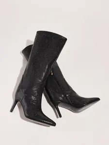 Detailed view of black snakeskin stiletto boots with pointed toe and side zipper