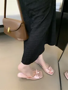 Nahaufnahme von rosa Satinsandalen mit Schleife und quadratischer Zehenpartie