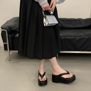 Close-up of black platform wedge flip-flops with thick soles and a stylish toe post design.