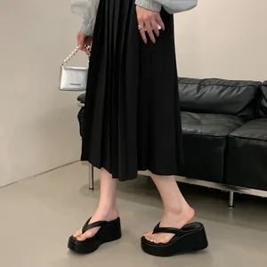 Close-up side view of stylish black wedge platform flip-flops showing the heel height and fit