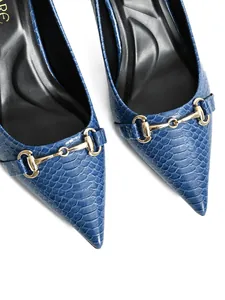 Close-up of blue croc-textured pumps with elegant gold horsebit buckle decoration.