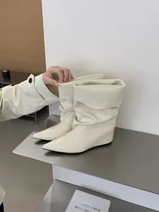 Close-up of cream white pointed-toe wedge boots with a stylish slouched design.
