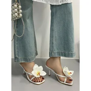 Elegant white high heel sandals with orchid flower detail on a square toe stiletto mule.