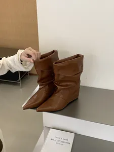 Close-up of stylish brown slouchy wedge boots featuring a pointed toe and folds