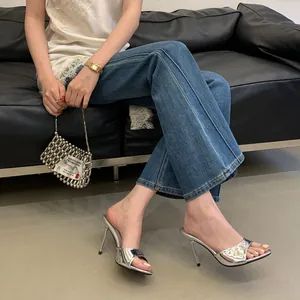 Close-up of silver metallic high heel mules worn by a model in a modern lifestyle setting