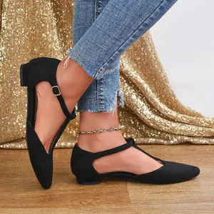 Detail of elegant black suede T-strap flat shoes with adjustable buckle for women.