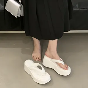 Close-up of white platform flip-flops with a quilted footbed on model's feet