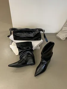 Fashionable set of black pointed-toe wedge slouchy boots and matching glossy handbag
