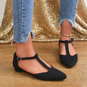 Elegant black T-strap flat shoes with closed toe on model for a stylish casual look.