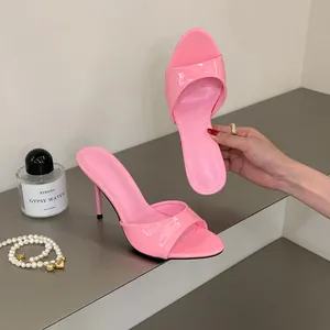 Elegant macro detail of pink patent leather stiletto mules featuring a sleek open-toe design