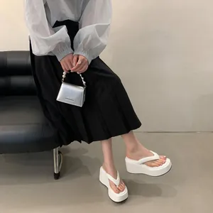 Close-up detail of white platform wedge flip-flops with a thick, comfortable sole.