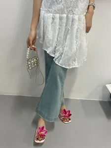 Close-up of pink square-toe sandals with elegant 3D flower decorations.