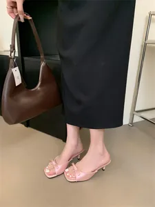 Elegante rosa Pantoletten mit Schleife und Pfennigabsatz zu einem schwarzen Rock