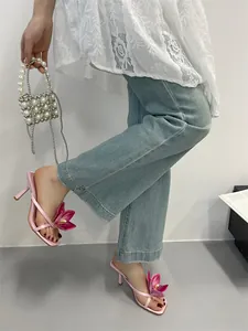 Elegant pink high heel sandals with large flower detail and square toe shown in use