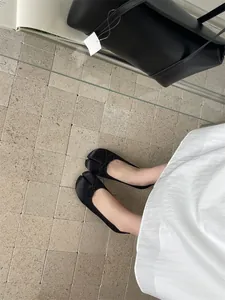 Detail view of elegant black tabi ballet flats with a delicate bow on a tiled floor