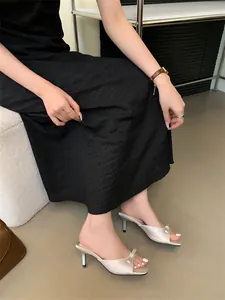 Elegante silberne Sandalen mit eckiger Zehenpartie und Schleife am Fuß getragen