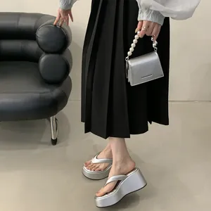 Close-up of silver platform wedge flip-flops with matching pearl handle handbag