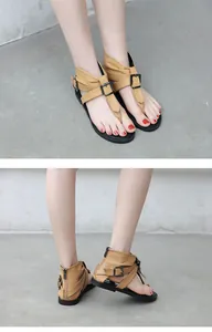 Detailed view of tan T-strap gladiator sandals with vintage buckle and back zipper