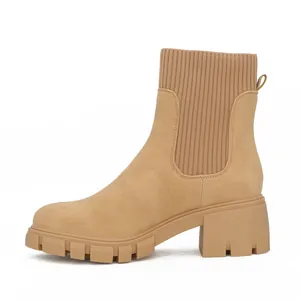 Detailed side view of tan suede-like Chelsea boots with chunky lug sole and ribbed knit