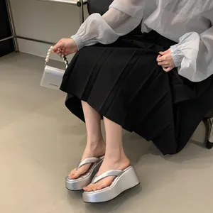 Silver platform wedge flip-flops shown in a stylish outfit with a black pleated skirt.