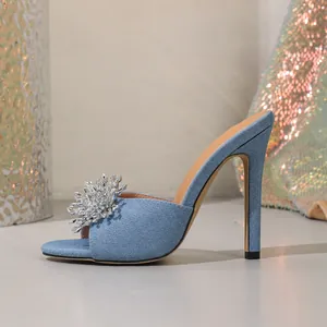 Seitenansicht von sexy hellblauen Denim-Mules mit hohen Absätzen und Strass-Blume