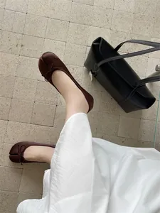 Top-down view of brown split-toe ballet flats featuring a bow on a tiled floor