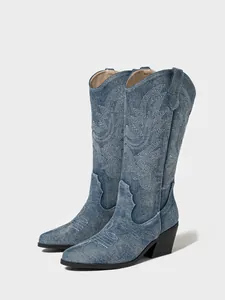 Detailed side view of blue denim western cowboy boots with intricate white embroidery detail.
