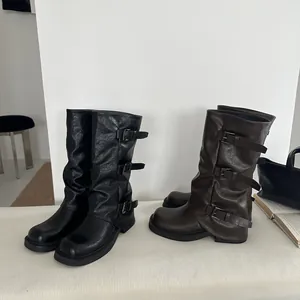 Schwarze und braune Westernstiefel mit drei Schnallen auf einem weißen Hintergrund