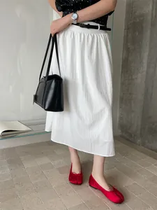 Elegant red satin Tabi split-toe flat shoes with bow, shown worn with a white skirt.