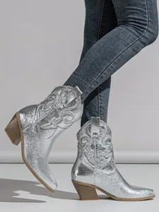 Close-up of silver metallic cowboy boots with embroidered patterns and block heels