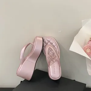Detailed view of fashionable pink platform wedge thong sandals with a quilted footbed texture.