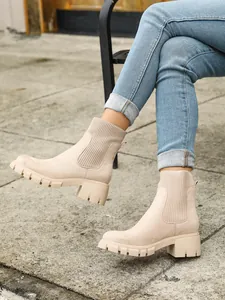 Stylish beige chunky heel Chelsea boots with knit detail worn with blue jeans outdoors