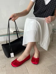Elegant red satin split-toe Tabi ballet flats with bow detail worn by a model