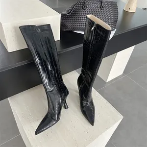 Detailed view of black croc-embossed knee-high boots with pointed toes and slim heels