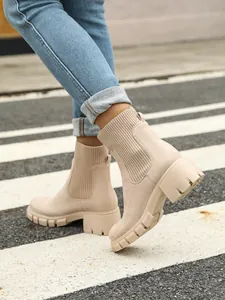 Side view of beige chunky knit Chelsea boots with platform soles on street crossing