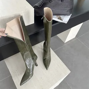 Close-up detail of olive green crocodile embossed knee-high boots with pointed toe