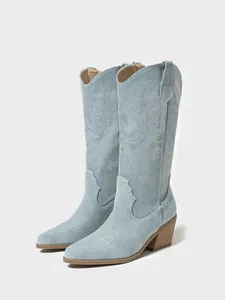 Side detail of light blue denim cowboy boots featuring western embroidery and pointed toe