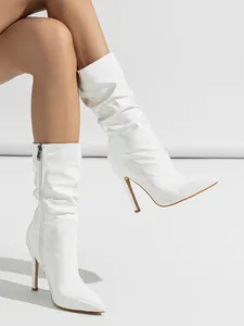 Side view detail of white patent leather slouch boots with stiletto heel and pointed toe.