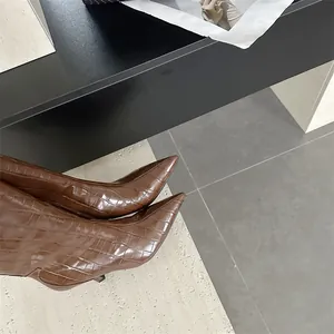 Macro view of brown faux crocodile texture pointed-toe boots with elegant thin heels
