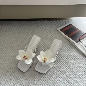 Detail view of white thong high-heeled sandals with large decorative 3D flower petals