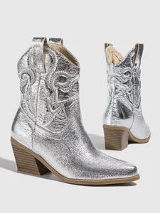 Detailed view of silver metallic cowboy boots with intricate embroidery and chunky heels
